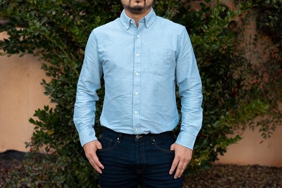 Flat lay of Free Assembly clothing pieces including a plaid flannel shirt, striped cardigan, and navy pinstripe blazer arranged on a neutral background